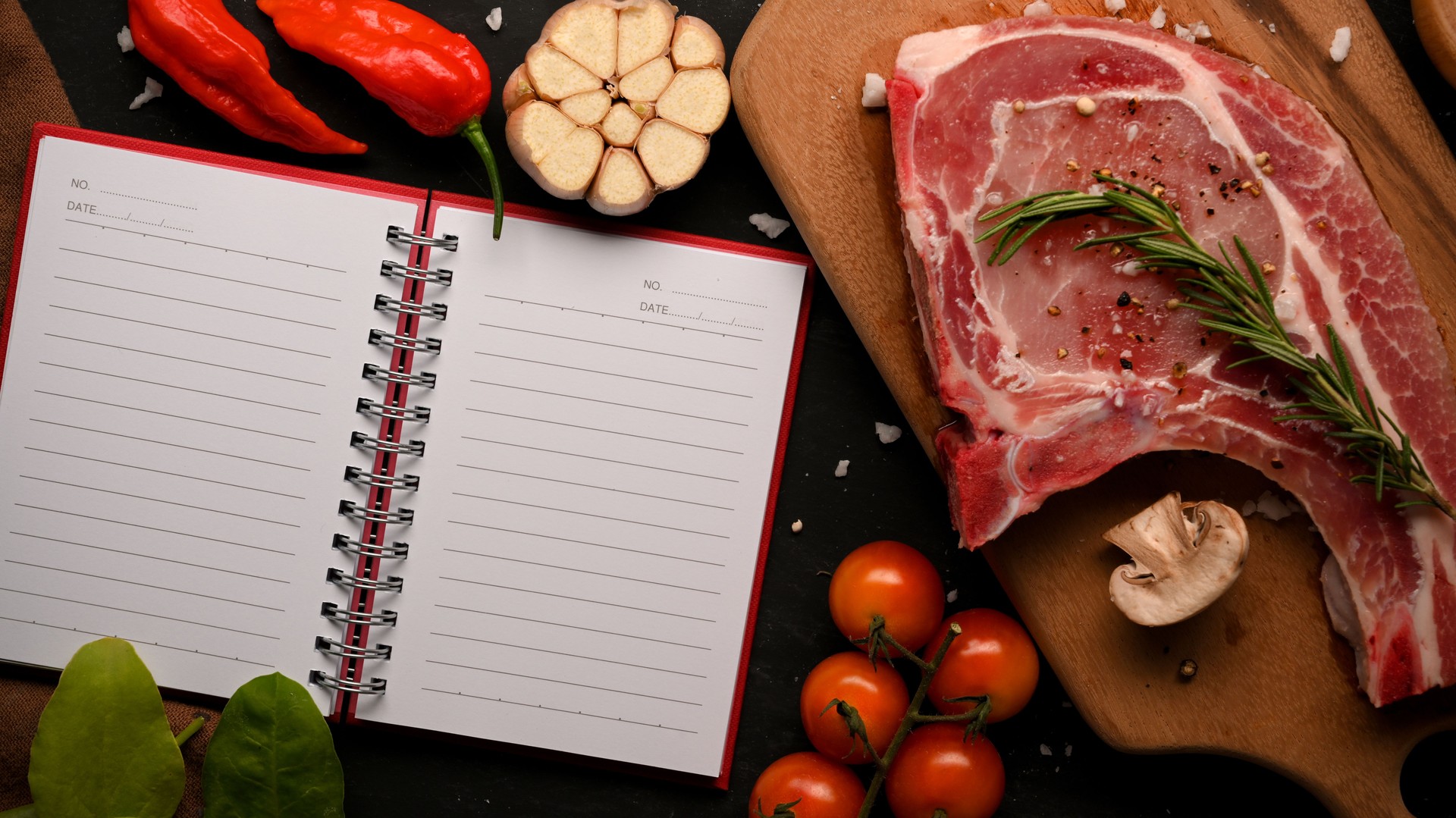 Raw pork chop steak on wooden board and food recipe book.