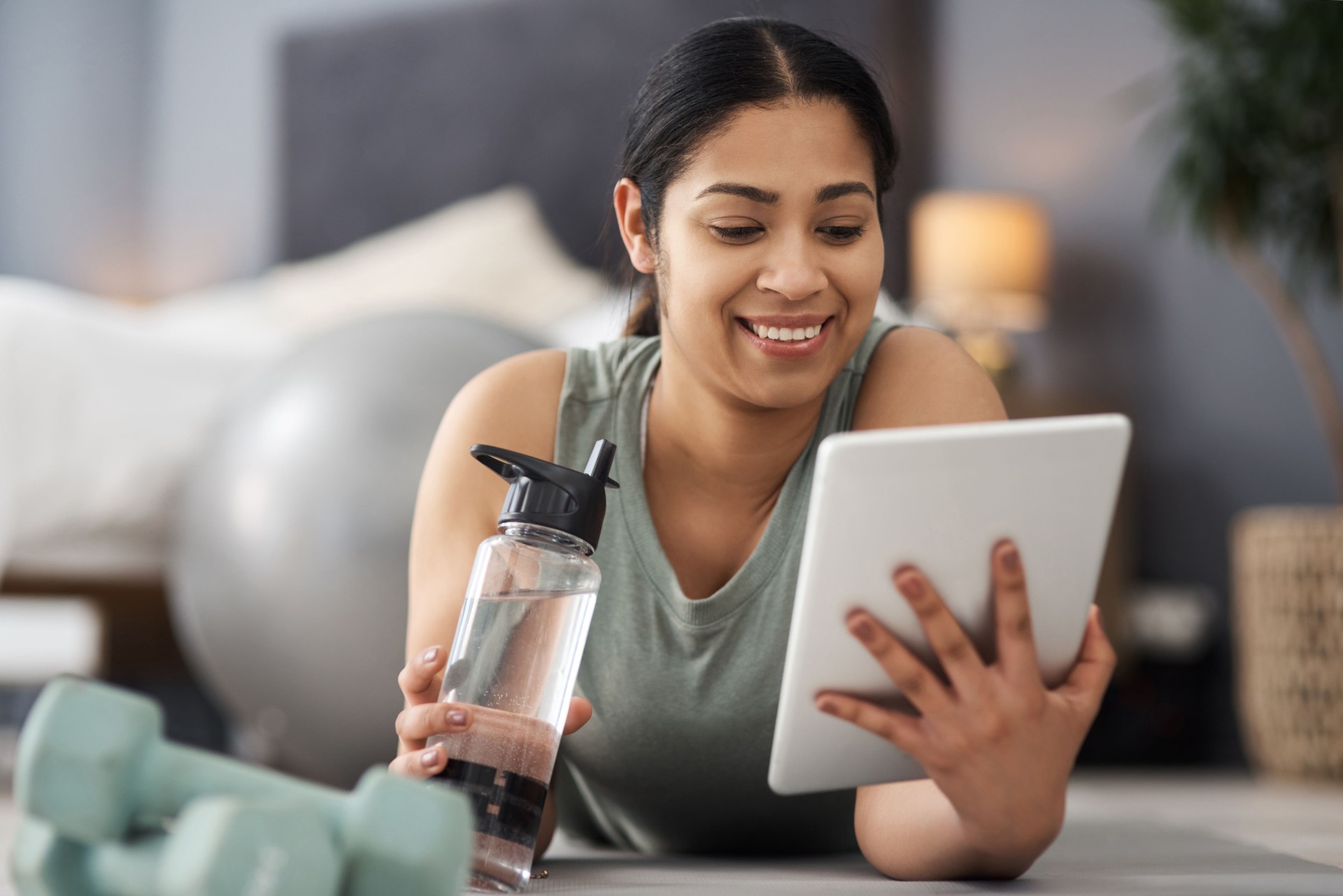Shot of a sporty young woman using a digital tablet while exercising at home