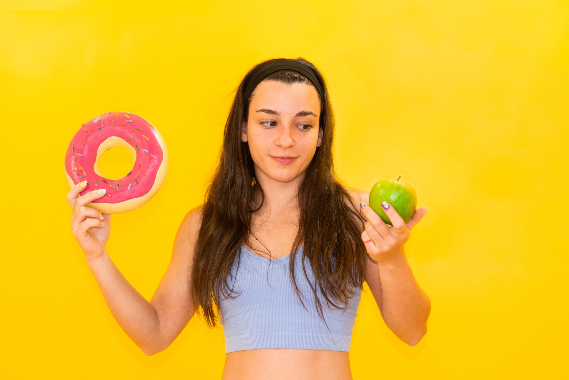 Choosing between a doughnut and an apple against a yellow backdrop