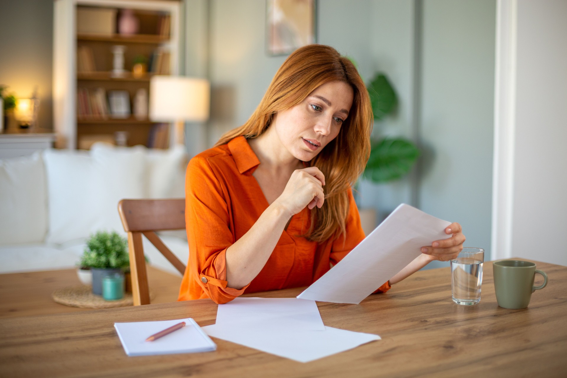 Focused woman reading documents at home office desk