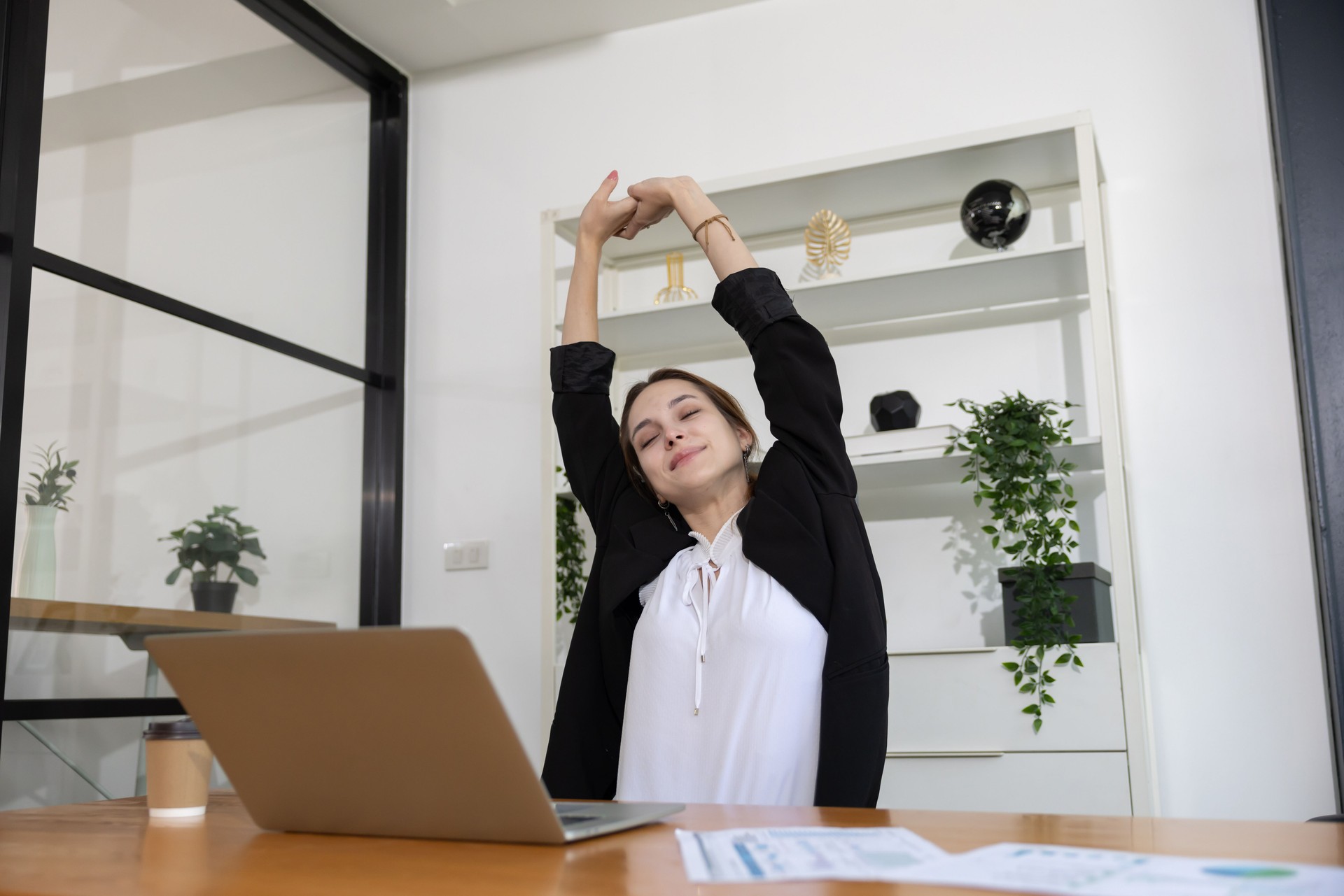 Happy businesswoman stretching her arms at her office table