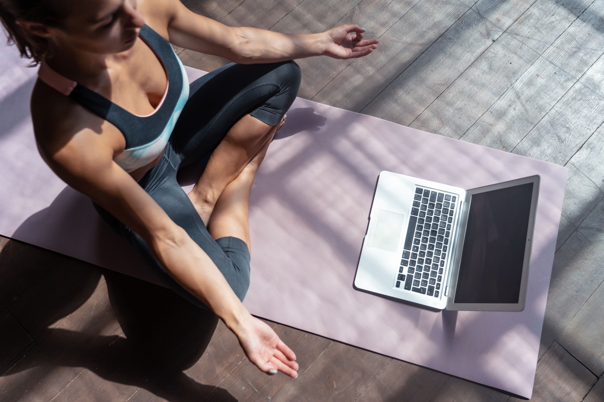 Top view young sporty slim woman coach video online training hatha yoga instructor modern laptop mockup screen meditate Sukhasana posture relax breathe easy seat pose gym healthy lifestyle concept